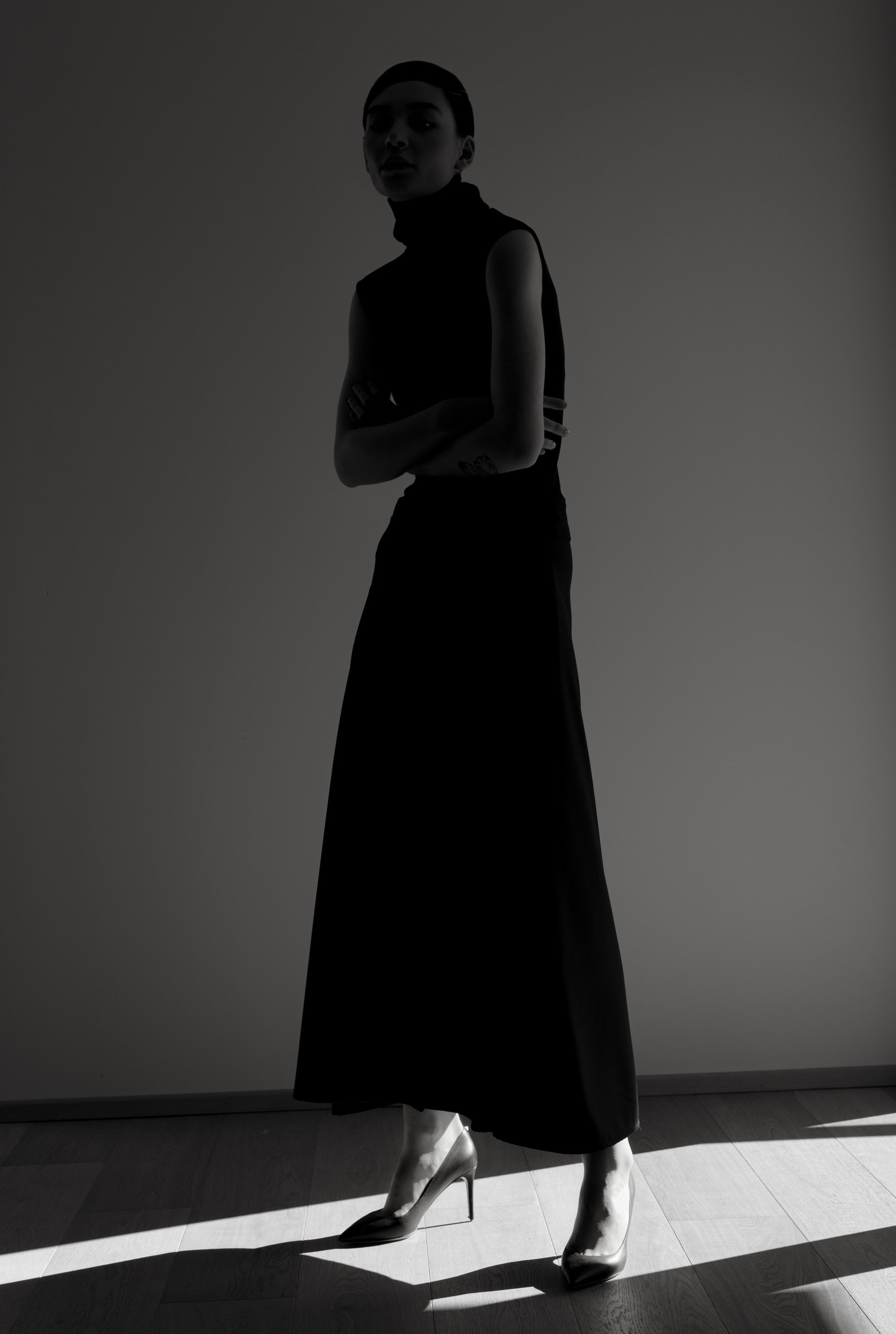 Woman in maxi dress standing in dark studio